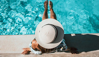 Frau mit Hut am Pool